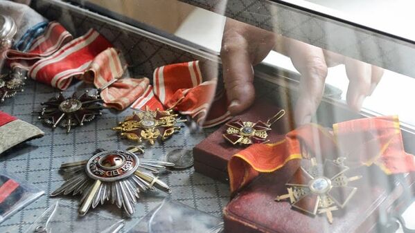 A hand reaches into the glass case holding Sergei Tsapenko's collection of Russian military medals on display at the Russian Cultural Center in Washington - Sputnik International