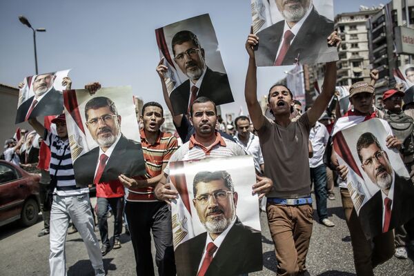 Mohamed Morsi supporters carry posters of the deposed leader as they march in Cairo Monday. - Sputnik International