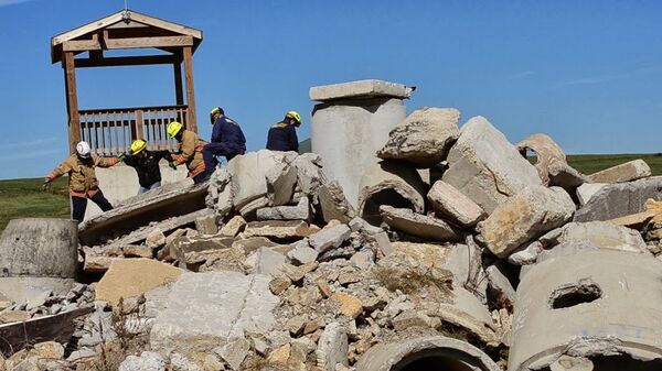 Fire and rescue workers help a woman from beneath rubble at an event to demonstrate the FINDER. - Sputnik International