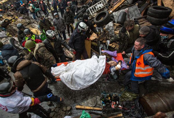 Protesters carry an injured comrade during a clash with riot police in Kiev Protesters carry an injured comrade during a clash with riot police in Kiev - Sputnik International