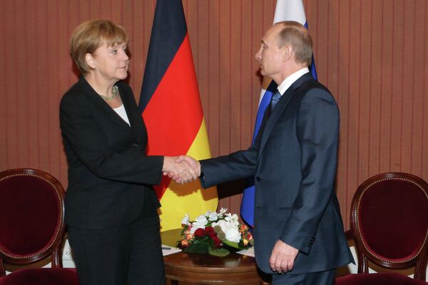 Vladimir Putin, shaking hands with Angela Merkel during his visit to Deauville, France. - Sputnik International
