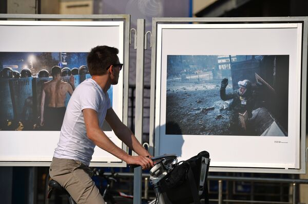 A man looking at  Andrei Stenin's exhibited photos. The journalist is still missing in Ukraine. - Sputnik International