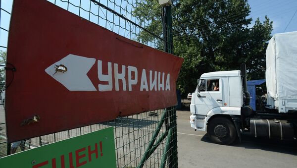 One of the trucks carrying humanitarian aid from Russia to east Ukraine passing a customs point of inspection. Sign on the fence reads: Ukraine. - Sputnik International