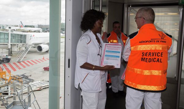 Paris airport doctors pose with copies of the leaflet which will be given to passengers arriving from Ebola infected zones, as they stand at the plane's arrivals bridge during a press visit at the Charles de Gaulle International Airport in Roissy, near Paris October 17, 2014. - Sputnik International